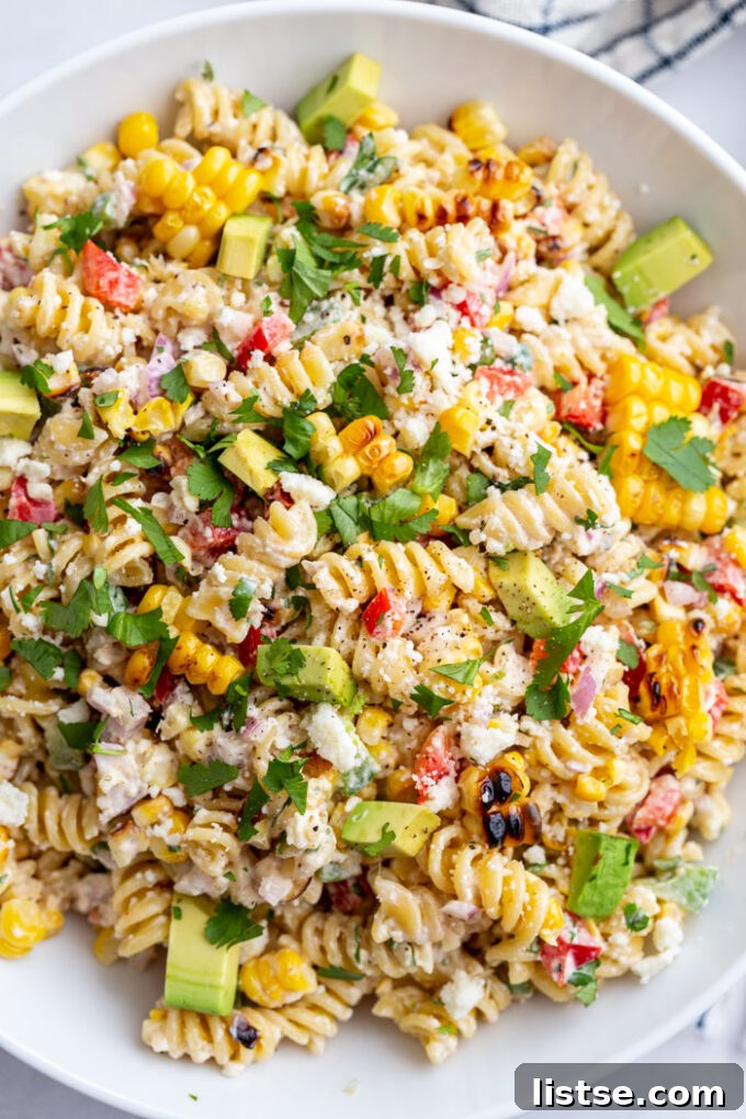Vibrant Elote Pasta Salad 5 A large serving of vibrant Mexican Street Corn Pasta Salad, perfectly showcasing the ideal blend of textures from tender rotini pasta, perfectly grilled corn, and crisp fresh vegetables, all beautifully coated in a rich and creamy dressing, ready to be enjoyed.