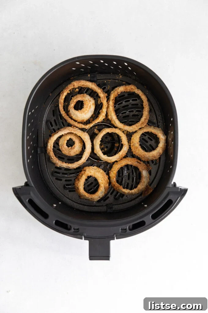 A basket full of freshly cooked, golden-brown air fryer onion rings, ready for serving.