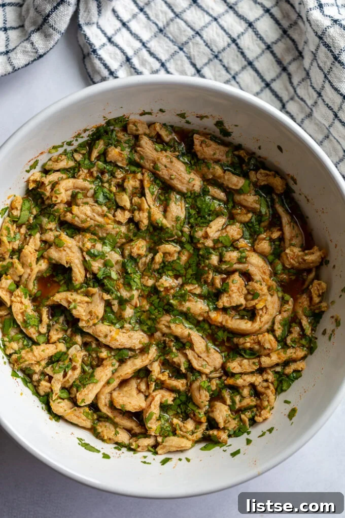 soy curls in a large white bowl marinating in liquid and cilantro