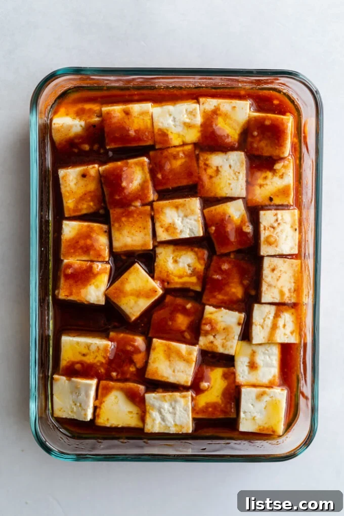 Grilled Tofu Feast 4 glass dish filled with tofu cubes that are covered in a dark colored marinade