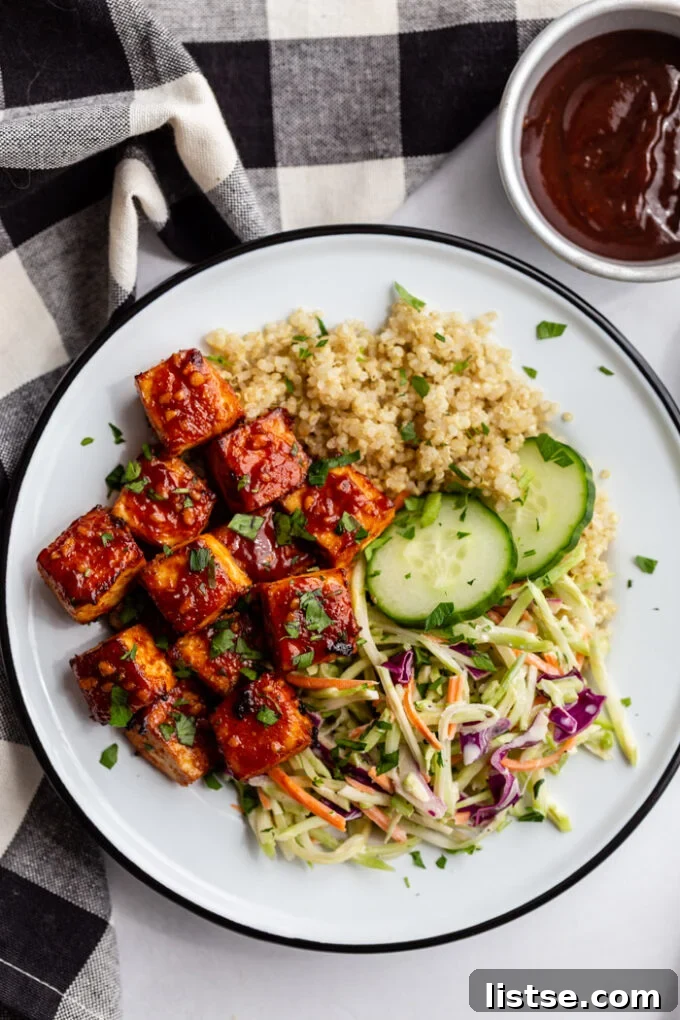 Grilled Tofu Feast 5 white bowl with quinoa, coleslaw, and bbq tofu in it plus a few pieces of cucumber