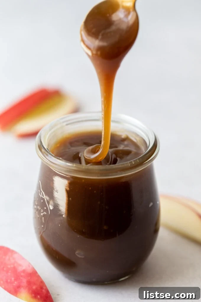 A small glass jar filled with rich, golden vegan caramel sauce, highlighting its silky texture.
