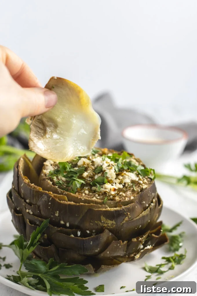 pulling a leaf off of a baked artichoke