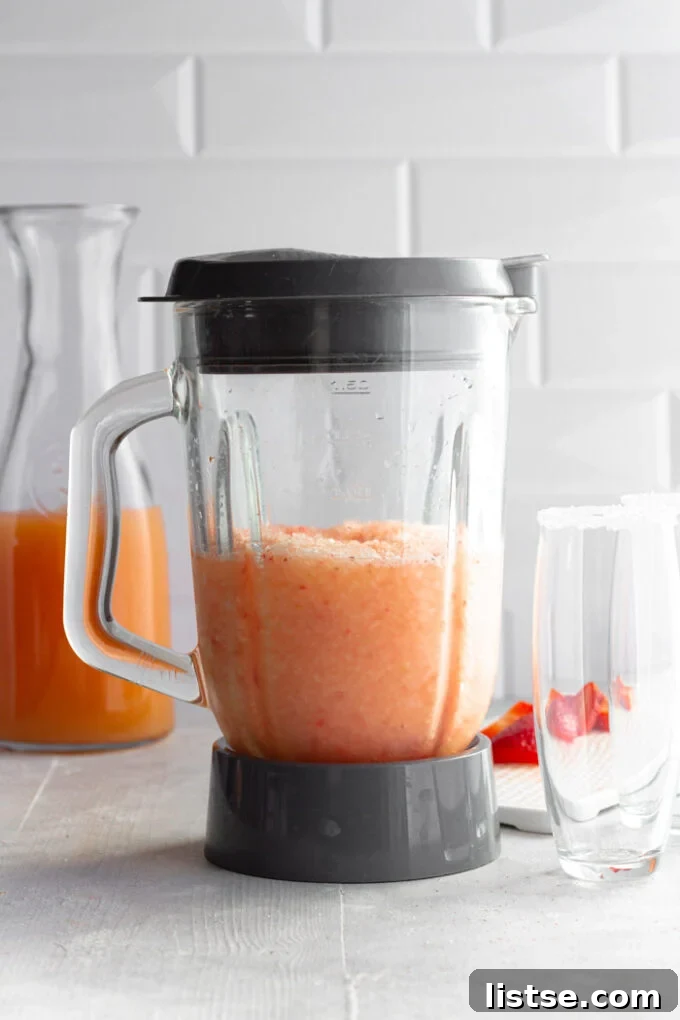 Blender filled with a smooth, frozen pink drink, showcasing the blended strawberry Salty Dog ready to serve.