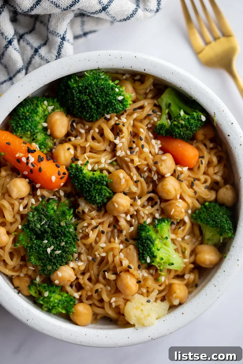 A vibrant, close-up shot of elevated ramen noodles brimming with fresh vegetables and garnished with sesame seeds.