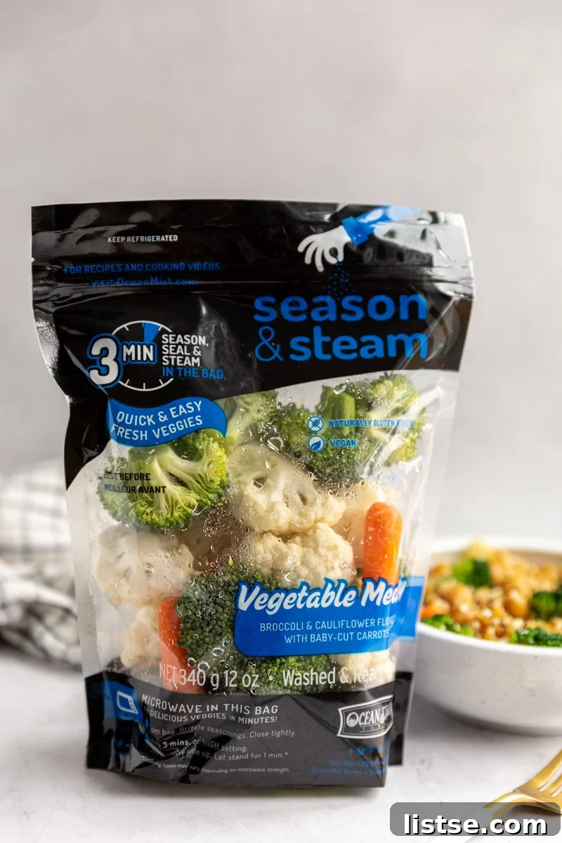 A standing bag of Ocean Mist Season & Steam Vegetable Medley with a steaming bowl of vegetable ramen in the soft background.