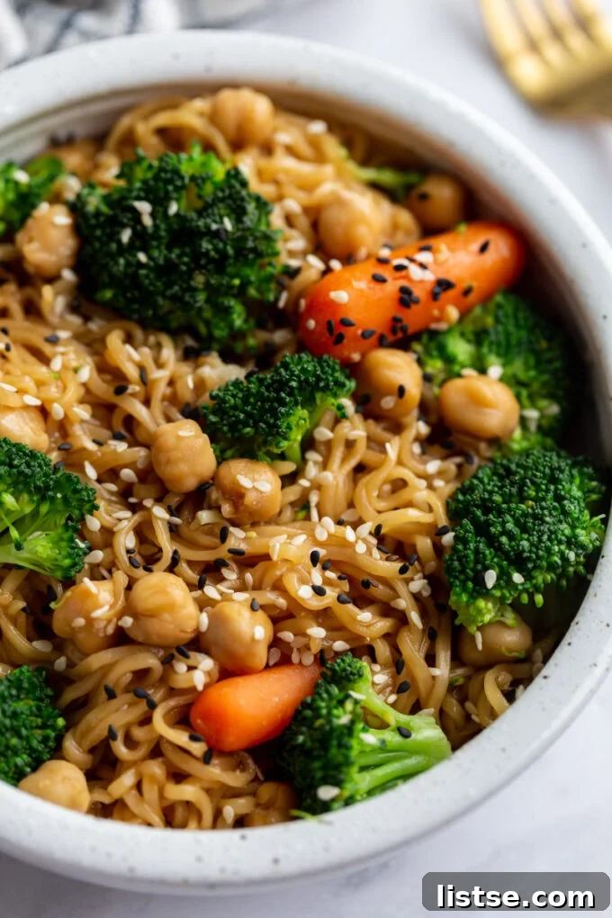 An appetizing close-up of steaming ramen noodles, adorned with colorful vegetables and a sprinkle of sesame seeds, ready to be enjoyed.