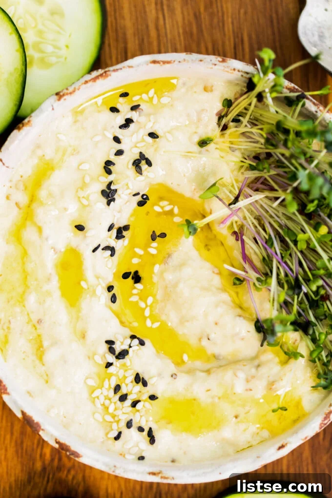 Close-up of creamy Baba Ganoush dip garnished with a generous drizzle of olive oil, sesame seeds, and a sprinkle of fresh herbs