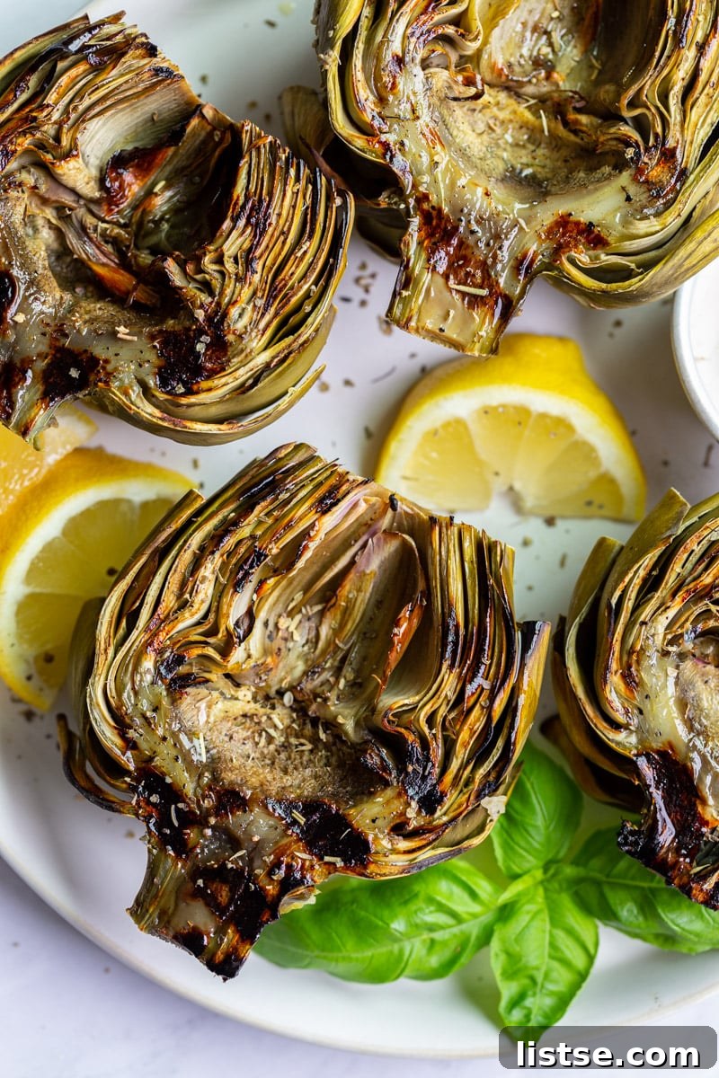 Fire-Kissed Artichokes 2 A large platter featuring four perfectly grilled artichokes, garnished with fresh lemon slices, ready to be enjoyed.