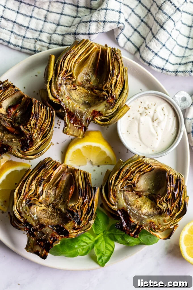 Fire-Kissed Artichokes 6 A full plate displaying four grilled artichokes, elegantly arranged with fresh lemon wedges.