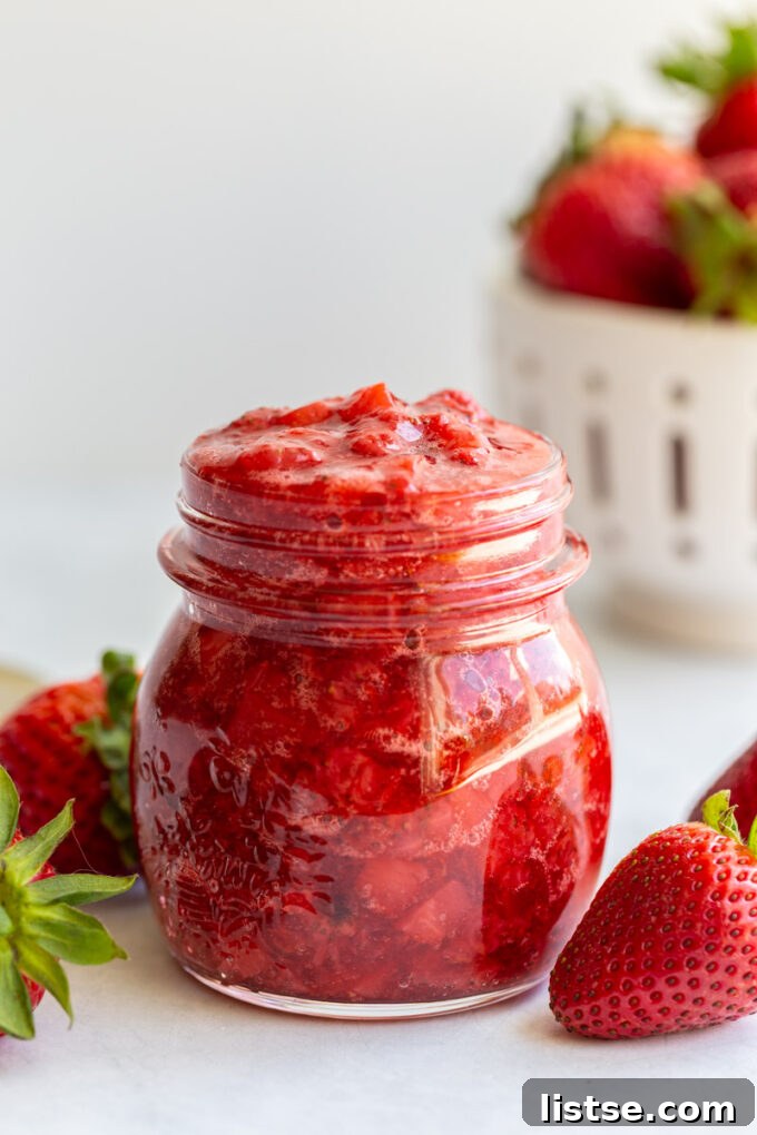 Strawberry compote in a jar near fresh strawberries