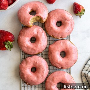 strawberry glazed donuts on a wire cooling rack with fresh strawberries around
