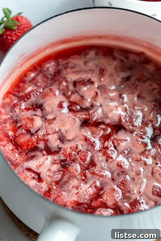 Making strawberry juice in a large pot, with fresh strawberries visible