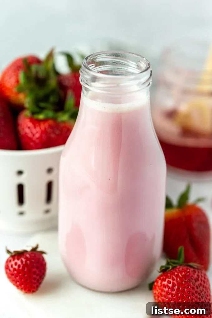 Glass jar filled with fresh homemade strawberry milk, ready to serve