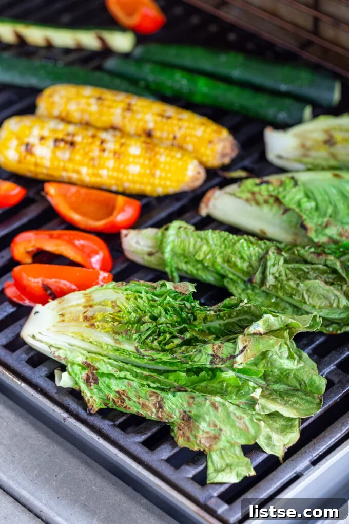 Grilled Summer Salad 5 A vibrant array of fresh vegetables – including romaine lettuce, red bell pepper, corn, and zucchini – expertly cooking on a hot grill, developing beautiful char marks.