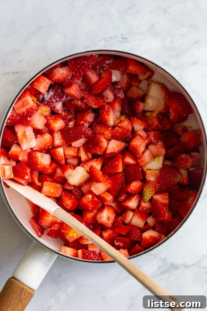 Close-up shot of vibrant red strawberry puree cooling in a pot, showcasing its rich color and thick texture.