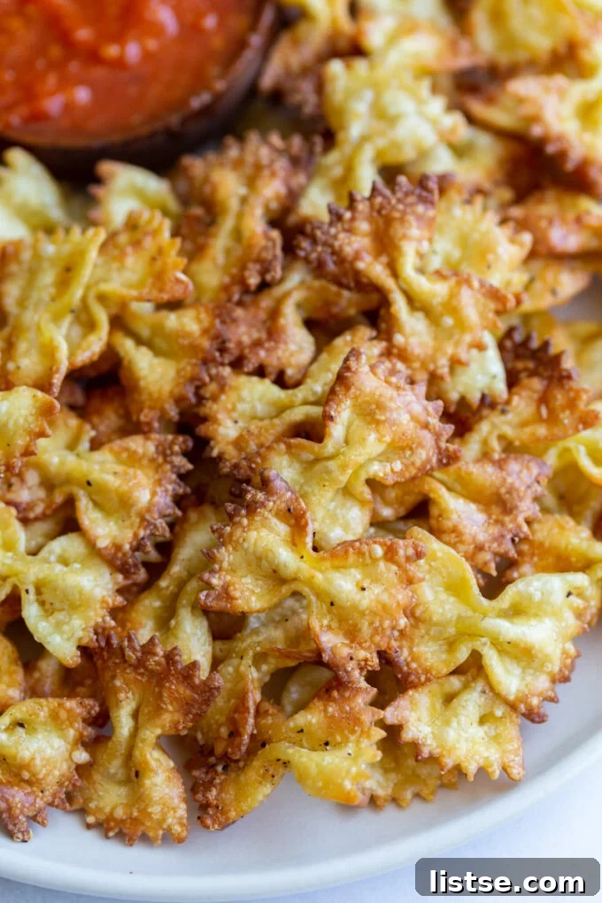 Crispy Pasta Bites 4 Up close shot of golden pasta chips on a plate with a small bowl of marinara dipping sauce