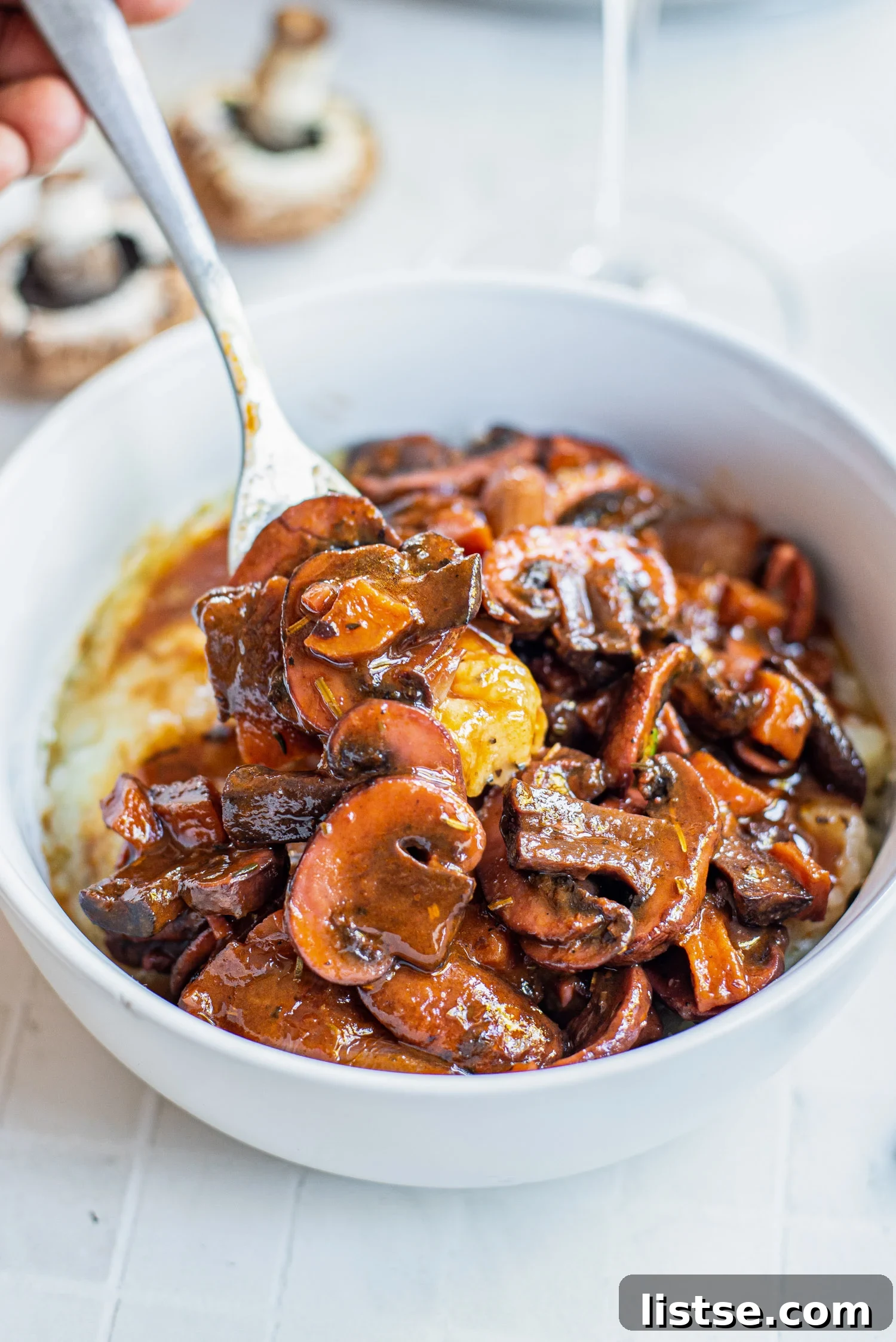 Fork in a bowl of mushrooms bourguignon served over mashed potatoes