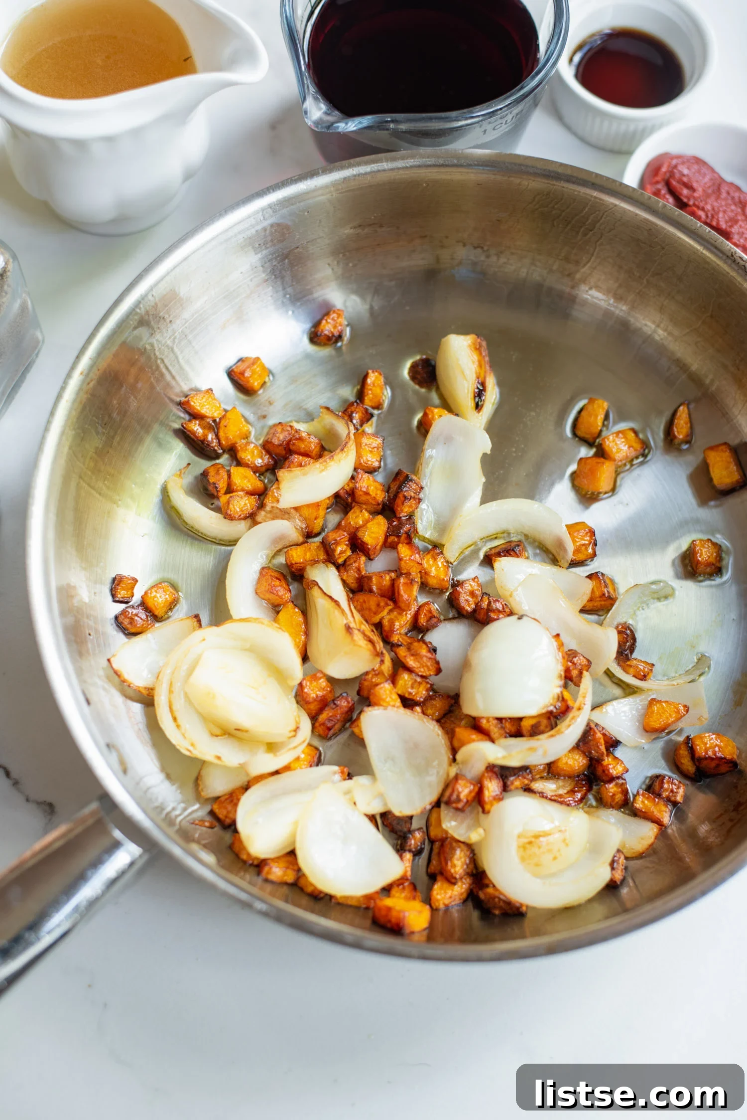 Onion and carrots sautéing in a skillet