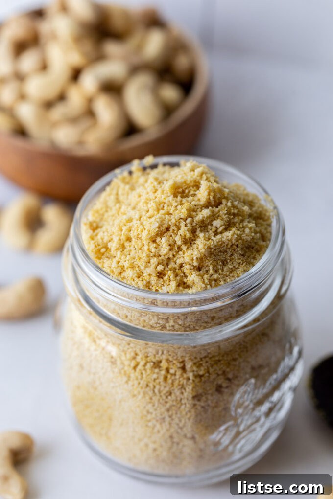 vegan parmesan cheese in a glass jar with cashews in the background
