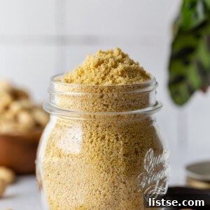 vegan parmesan cheese in a glass jar with cashews in the background