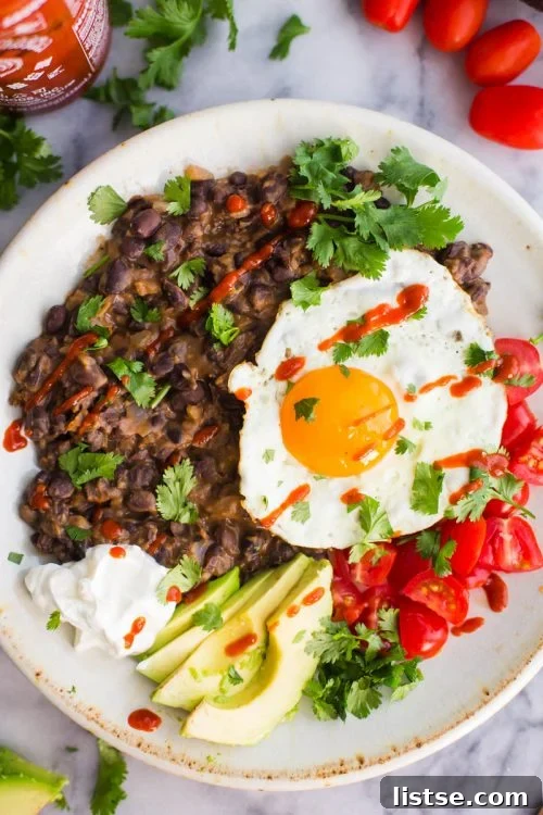 mashed blck beans on a plate with a fried egg and veggies