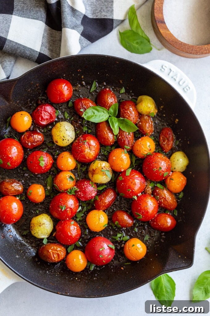 Cast iron skillet filled with beautifully blistered cherry and grape tomatoes, ready to be served.
