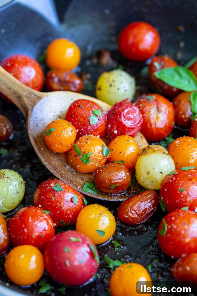 Close-up shot of a spoonful of blistered tomatoes, showcasing their juicy texture and vibrant color.