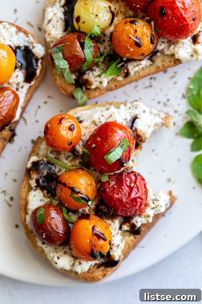 Blistered tomatoes elegantly served over toast with a balsamic glaze drizzle and fresh basil leaves.