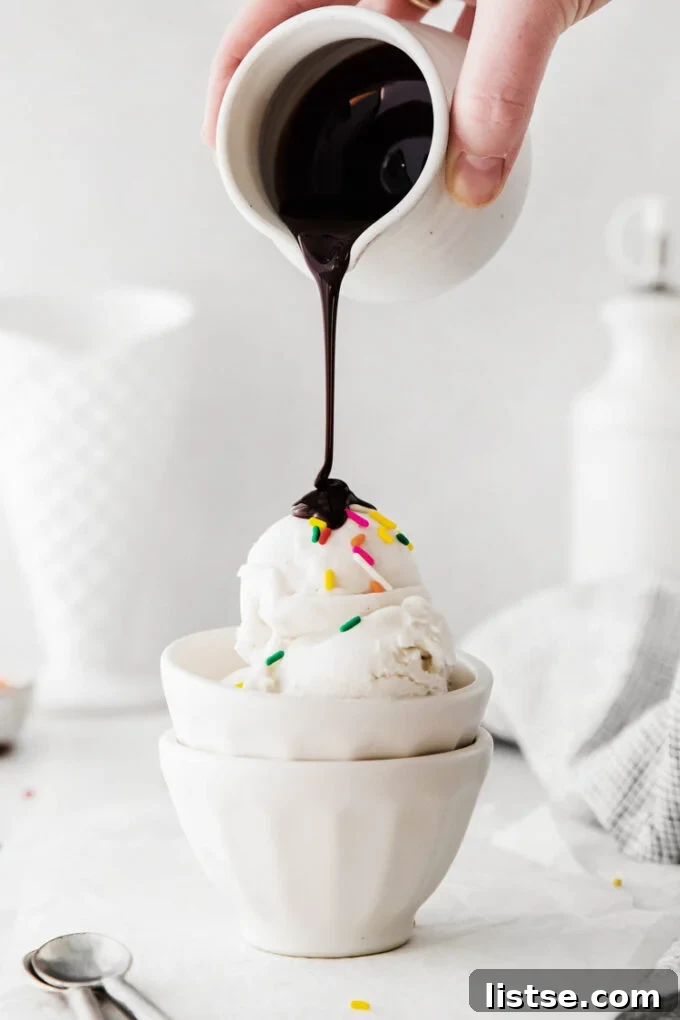 Creamy Vegan Dreams 5 A hand drizzling rich chocolate sauce over a scoop of vegan ice cream, creating a tempting dessert.