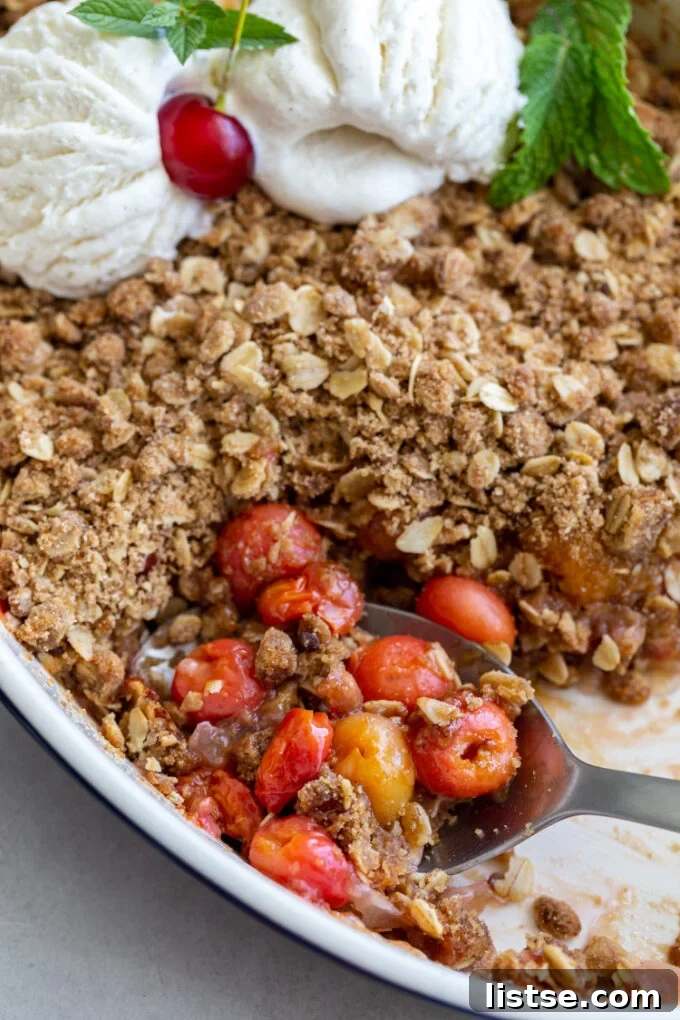 Sweet Cherry Crumble 3 A spoon scooping into a warm cherry crisp, revealing the juicy cherry filling and crispy topping