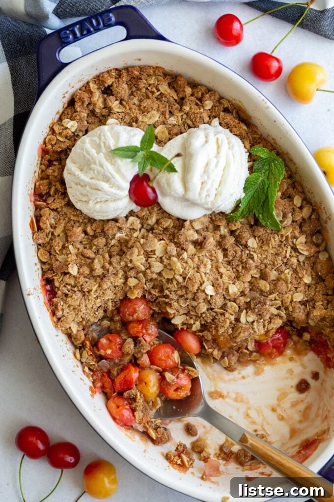 Sweet Cherry Crumble 4 A spoon dishing into a baked cherry crisp from a white baking dish