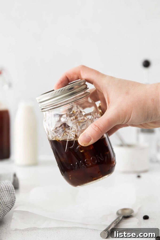 Espresso and homemade brown sugar syrup being vigorously shaken in a mason jar with ice, demonstrating the essential step for frothy shaken espresso.