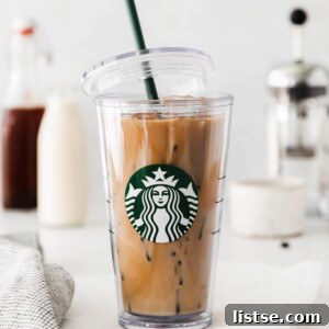 A tall glass of homemade Iced Brown Sugar Oatmilk Shaken Espresso, perfectly replicating the Starbucks version, with a lid resting beside it.