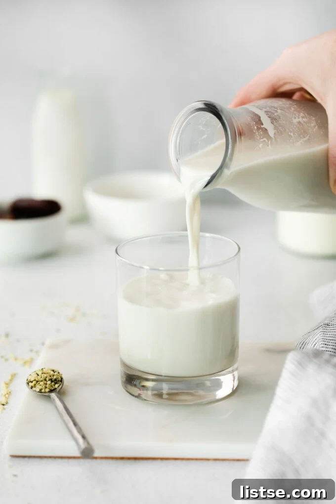 pouring homemade hemp milk into a glass