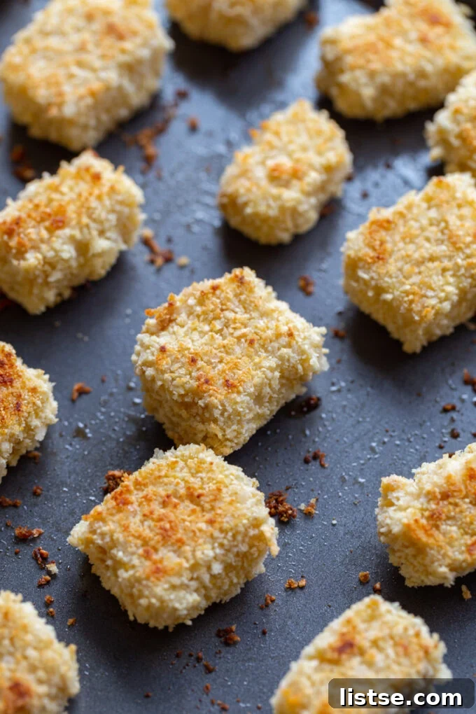 Crispy tofu pieces lined up neatly on a baking sheet, ready for the oven.