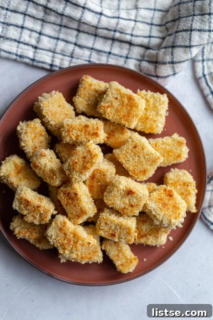 Several panko crusted tofu cubes beautifully arranged on a dark red plate, highlighting their crispy texture.