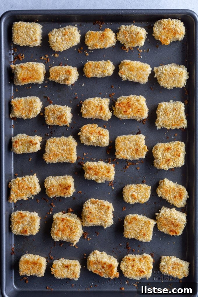 A close-up shot of crispy tofu pieces cooling on a baking sheet after being cooked.