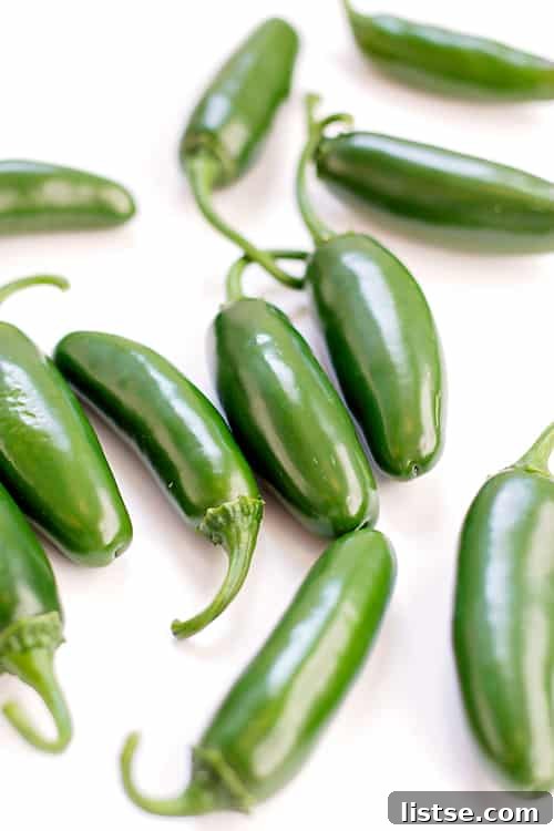 Vibrant green jalapeno peppers neatly arranged on a pristine white background.