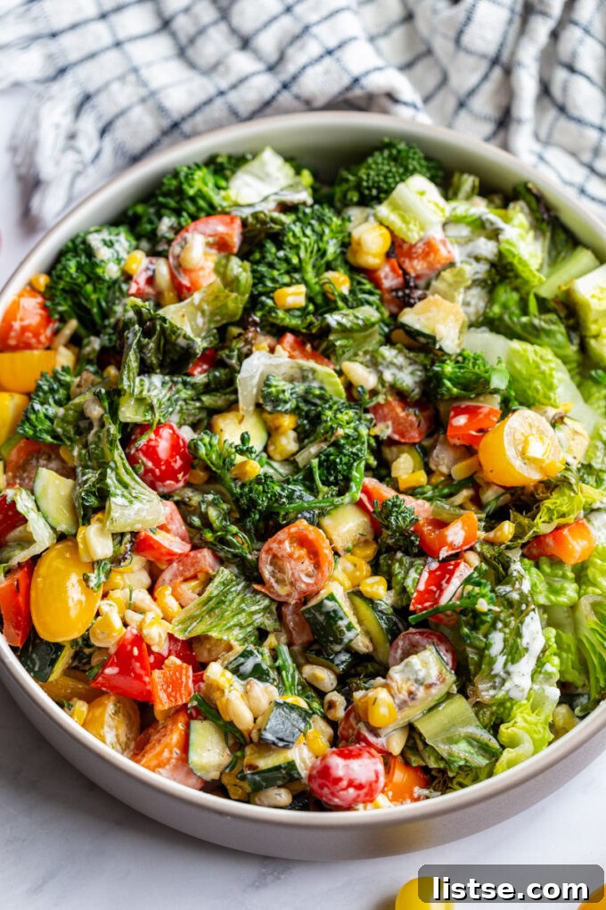 Fresh garden salad in a large wooden bowl with mixed greens, cherry tomatoes, cucumbers, bell peppers, and a light vinaigrette.