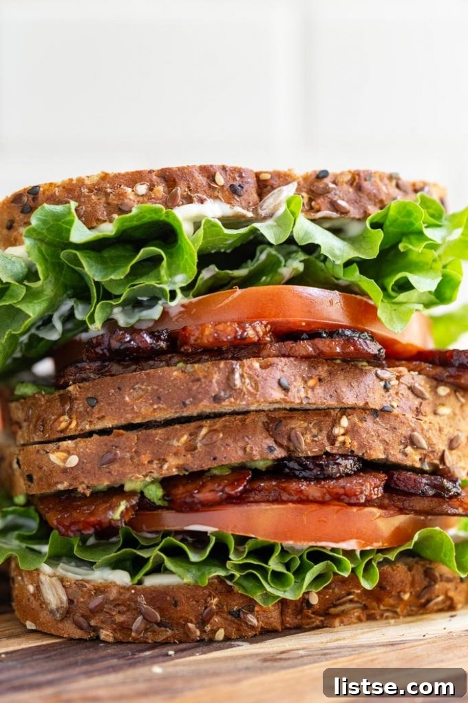A delicious vegan BLT sandwich with crispy tempeh bacon, fresh green lettuce, and ripe red tomato slices on toasted bread.