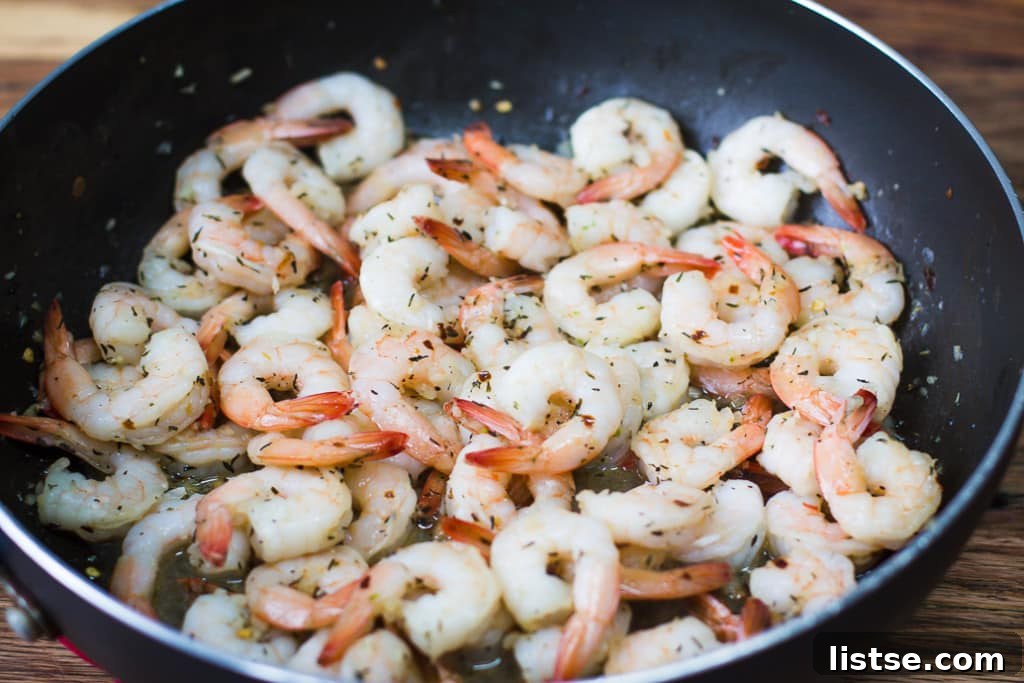 Succulent shrimp sizzling in a hot skillet with garlic, butter, and fresh parsley, ready for a delicious meal.