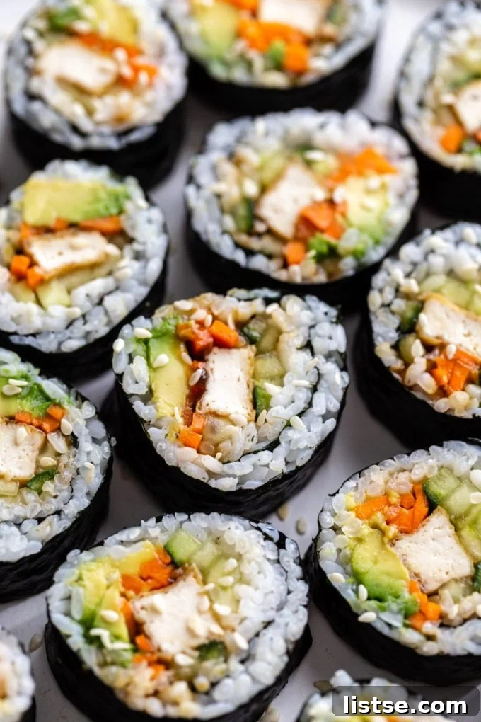 An array of colorful vegan tofu sushi rolls with avocado, cucumber, bell peppers, and other fresh vegetables, perfectly arranged.