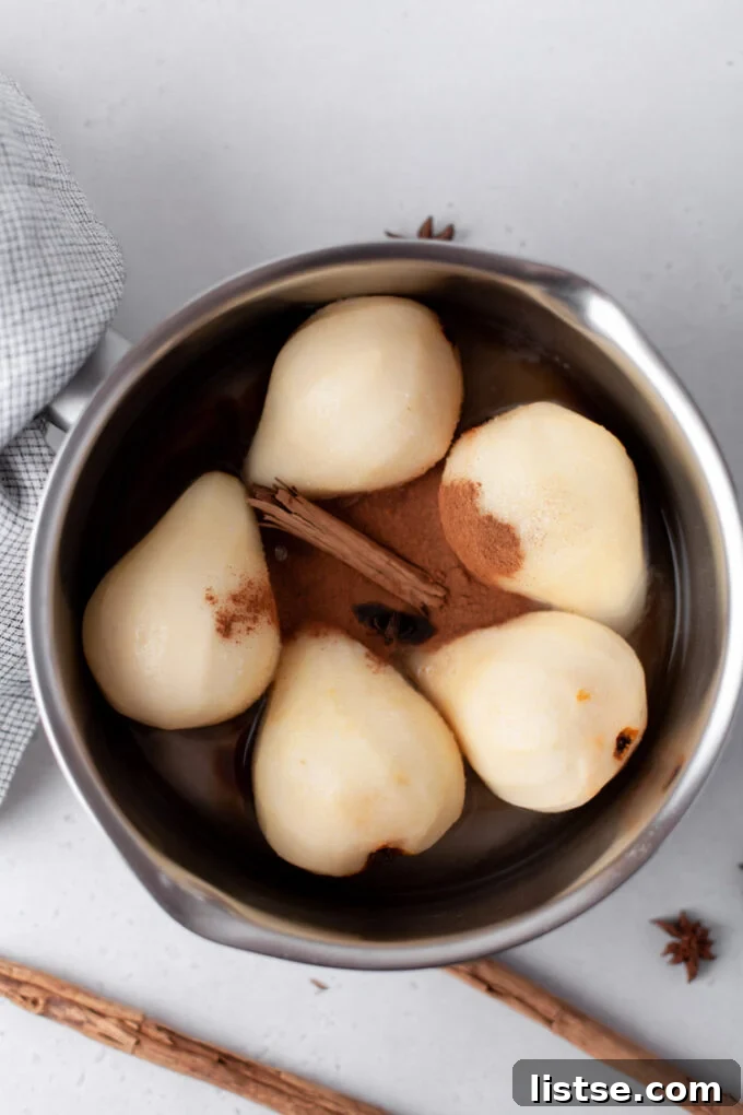 Velvet Vanilla Pears 3 Adding peeled pears to a large pot with a cinnamon stick and star anise for poaching.