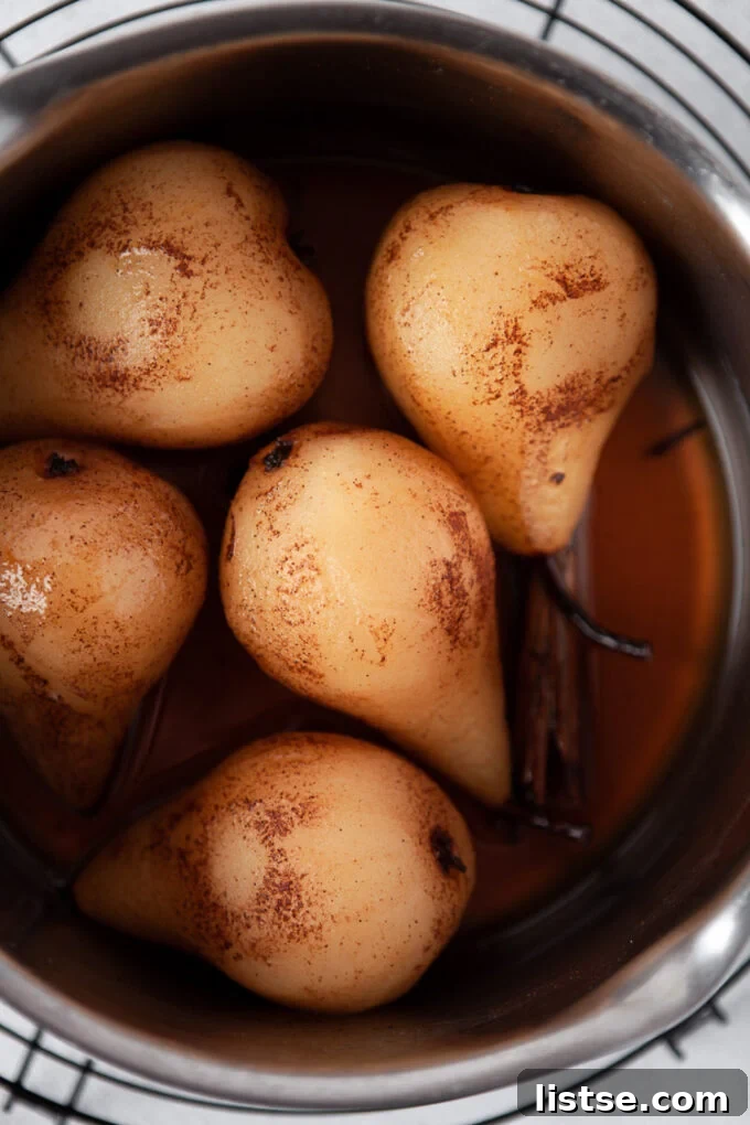 Velvet Vanilla Pears 4 Pears cooking in a fragrant spiced vanilla syrup in a large pot, ready to be served.