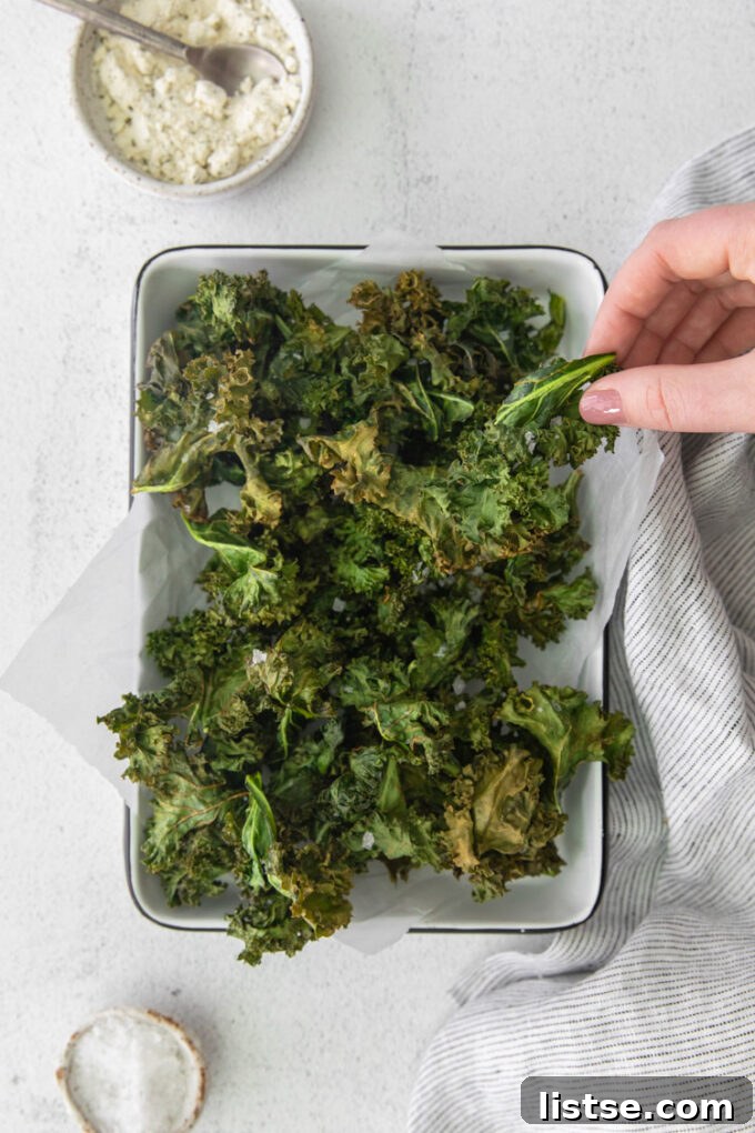 Crispy Air Fryer Kale Delight 3 woman's hand grabbing a kale chip out of a serving tray