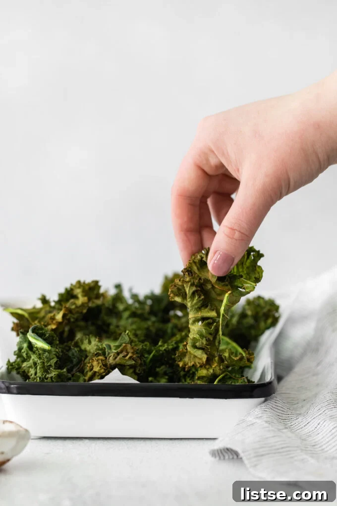 Crispy Air Fryer Kale Delight 5 hand grabbing air fryer kale chips off of a serving plate