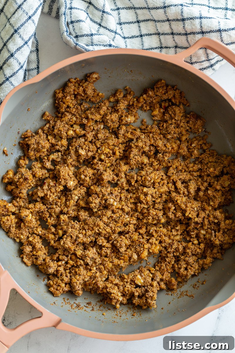Close-up shot of rich mushroom and walnut taco meat simmering in a vibrant pink skillet, perfectly seasoned and ready to serve.