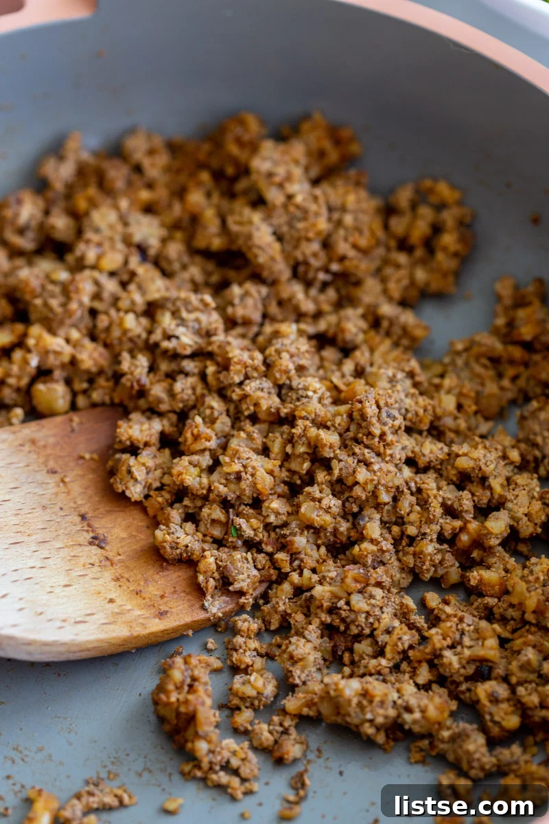 A vibrant close-up of perfectly seasoned mushroom taco meat, cooked to a golden crisp in a charming pink skillet, ready to be served.
