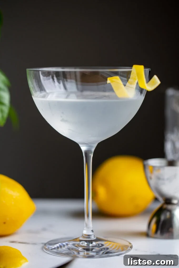 A pristine Vesper cocktail served in a classic martini glass, garnished with a delicate lemon twist, set against a blurred background, evoking sophistication.